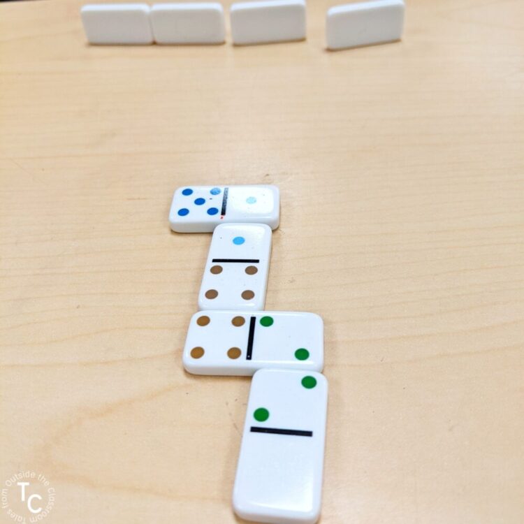 4 dominoes lined up in game with other dominoes set up for a player in an addition game