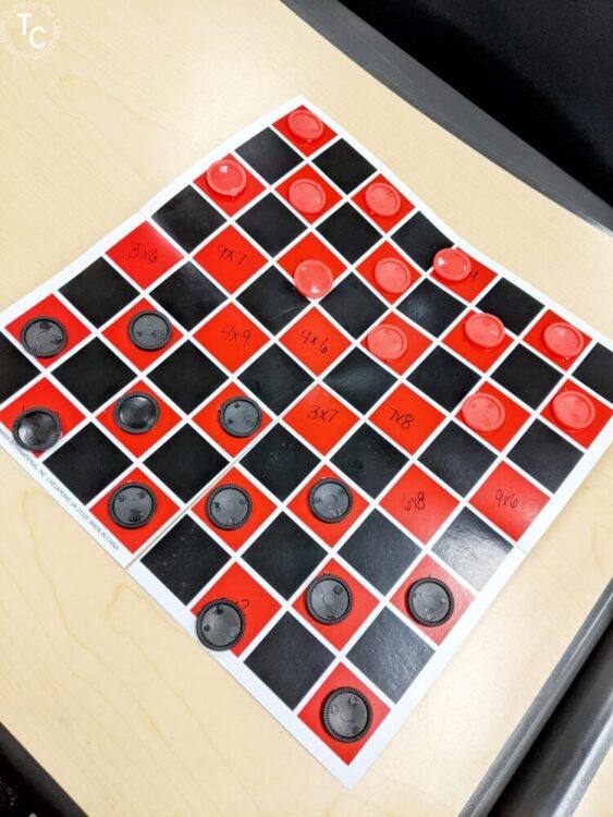 Checkers gameboard with multiplication facts written on it and game pieces set up